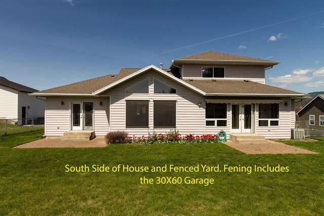 rear view of house with fence, french doors, and a lawn
