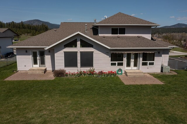 rear view of property featuring a mountain view, french doors, fence, and roof with shingles