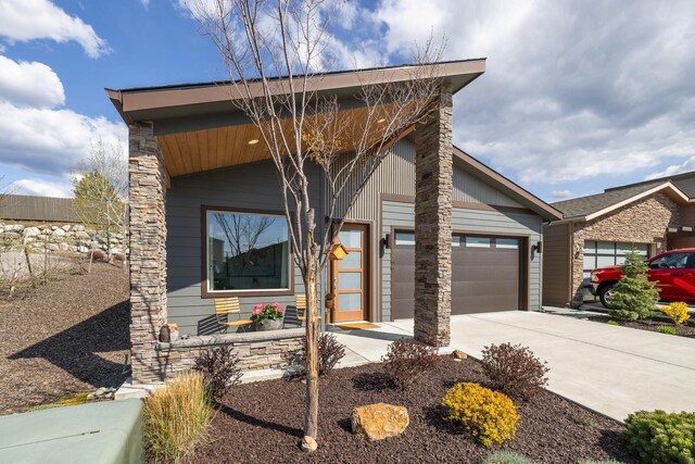 3306 N Ladalia Dr, Coeur D Alene, ID 83814 - view of front of property with concrete driveway, stone siding, a garage, and covered porch