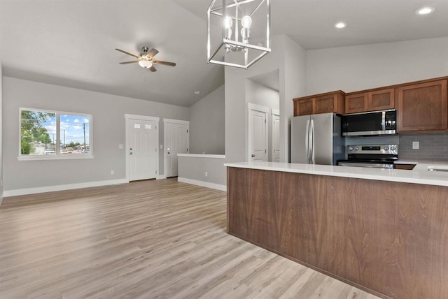 kitchen featuring appliances with stainless steel finishes, light countertops, baseboards, a ceiling fan, and open floor plan