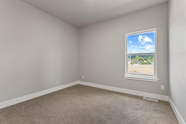 carpeted spare room with visible vents and baseboards