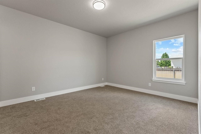 spare room featuring baseboards, visible vents, and carpet floors
