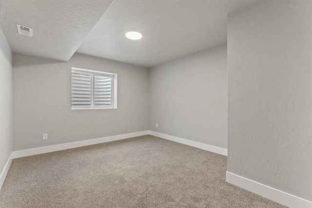 carpeted empty room with baseboards, visible vents, and a textured ceiling