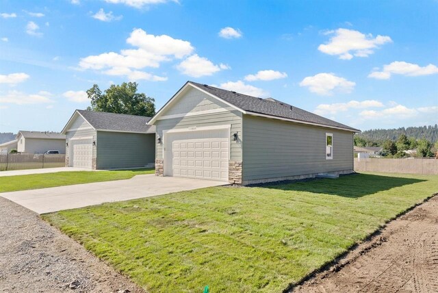 view of home's exterior with a garage, fence, concrete driveway, and a lawn