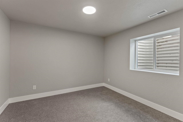 carpeted spare room featuring visible vents and baseboards