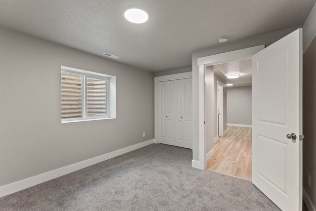 unfurnished bedroom featuring carpet, visible vents, a closet, and baseboards