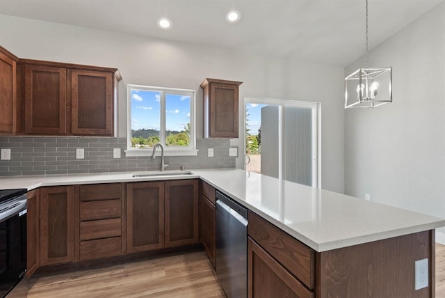 kitchen featuring decorative backsplash, a sink, light wood-style floors, stainless steel appliances, and a peninsula