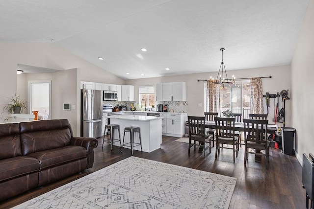 living area with an inviting chandelier, lofted ceiling, dark wood finished floors, and recessed lighting