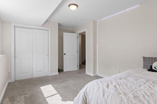 carpeted bedroom featuring baseboards and a closet