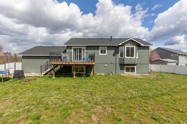 back of property with stairs, a trampoline, a deck, fence, and a yard
