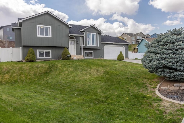 exterior space with a garage, a shingled roof, a lawn, concrete driveway, and fence