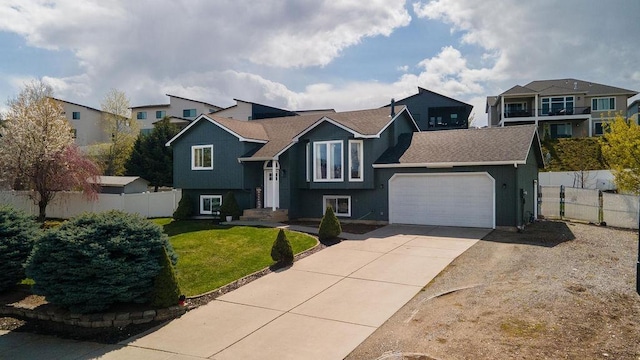 split foyer home with concrete driveway, a residential view, a front yard, fence, and a garage