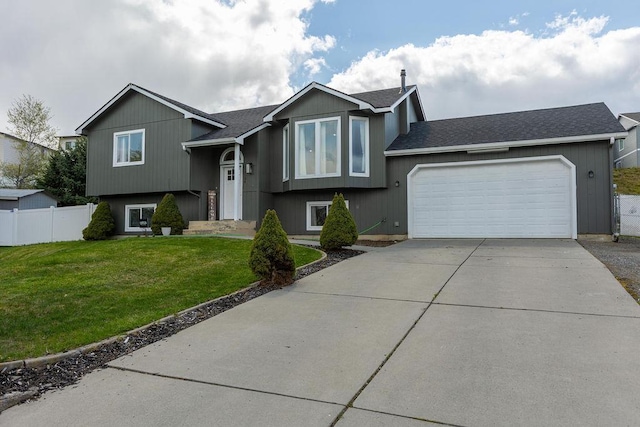 split foyer home with driveway, fence, a front yard, and an attached garage