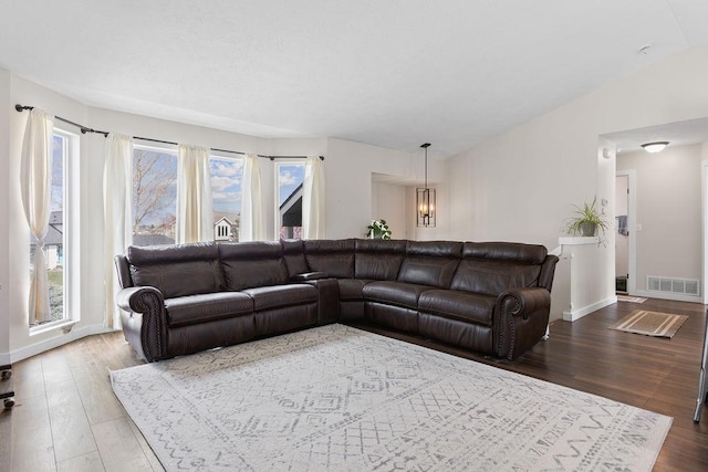 living area featuring wood finished floors, visible vents, vaulted ceiling, and baseboards