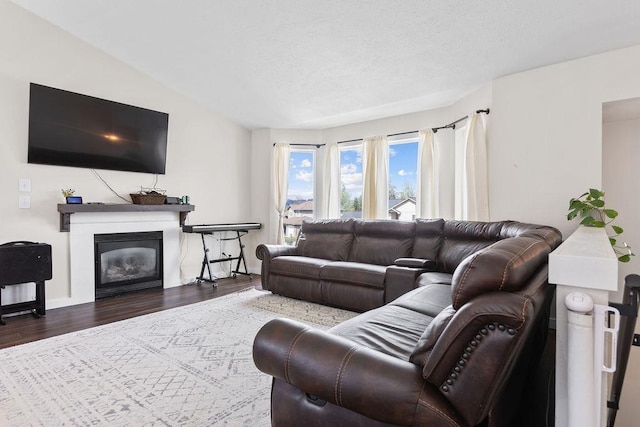 living room with a textured ceiling, baseboards, wood finished floors, and a glass covered fireplace