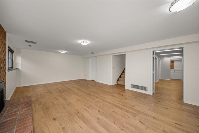 2711 S Pittsburg St, Spokane, WA 99203 - unfurnished living room with stairs, light wood-style flooring, baseboards, and a brick fireplace