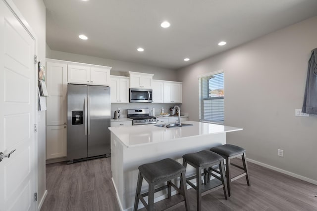 kitchen with a kitchen bar, a sink, appliances with stainless steel finishes, and dark wood-style flooring
