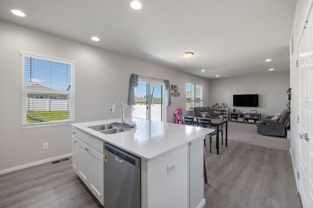 kitchen featuring a sink, visible vents, white cabinetry, stainless steel dishwasher, and an island with sink