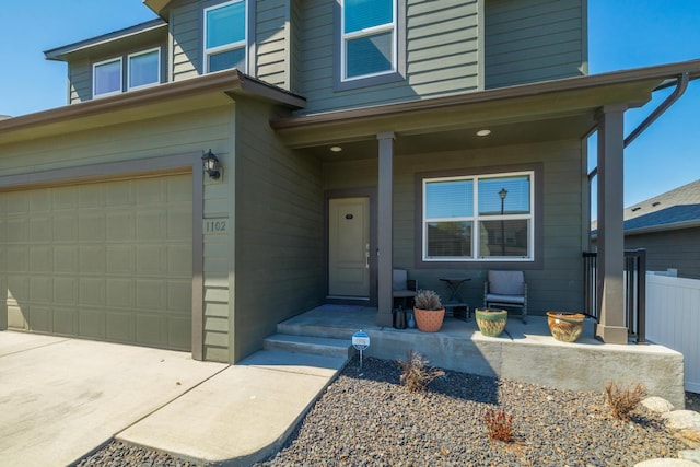 property entrance featuring fence, a porch, and an attached garage
