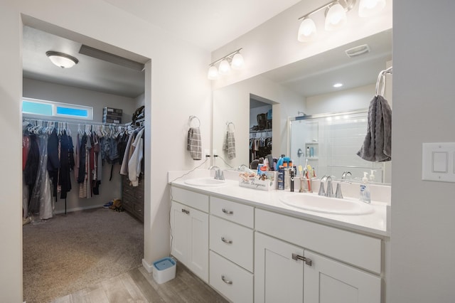 full bathroom with double vanity, wood finished floors, a shower stall, and a sink