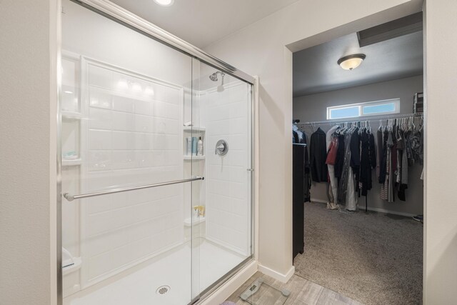 full bath with baseboards, a shower stall, wood finished floors, and a spacious closet