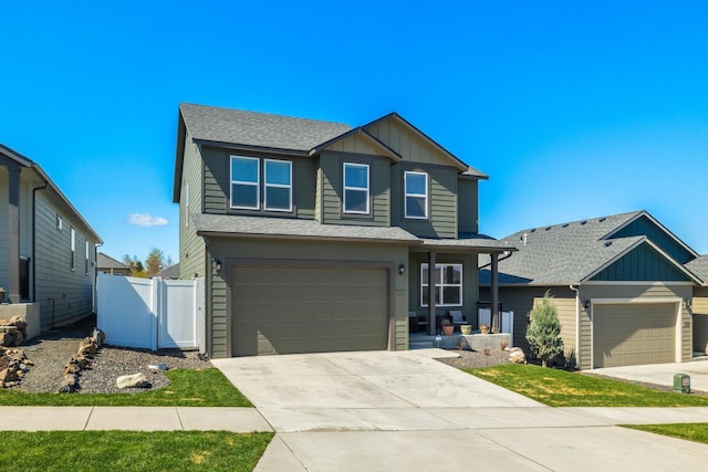 craftsman-style home with driveway, a shingled roof, board and batten siding, and fence