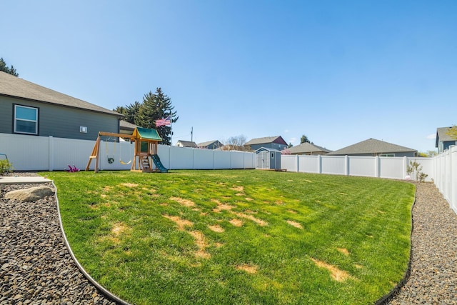 view of yard with a storage shed, a playground, and a fenced backyard