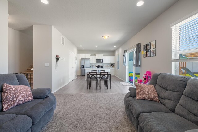 living area with visible vents, light wood-type flooring, and recessed lighting