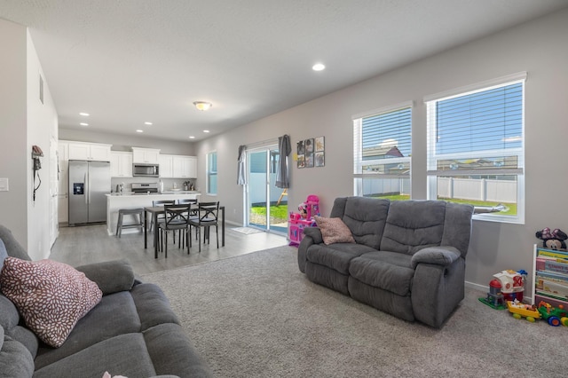living area with visible vents, light wood-type flooring, recessed lighting, and baseboards
