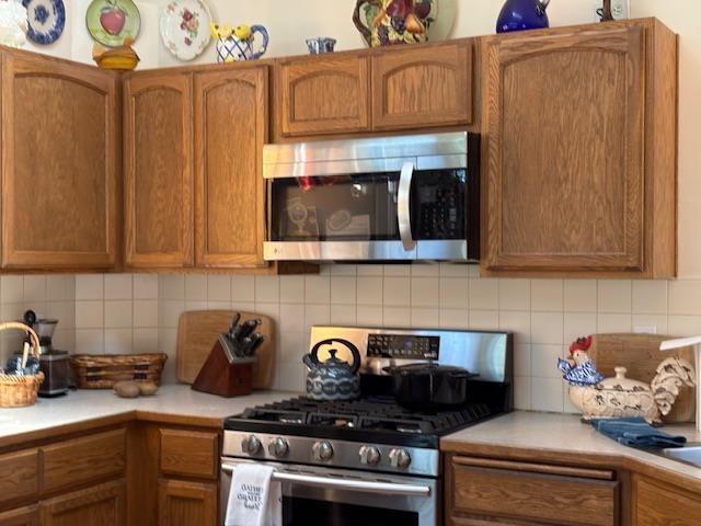 9306 E Lake Rd, Elk, WA 99009 - kitchen featuring brown cabinetry, light countertops, decorative backsplash, and appliances with stainless steel finishes