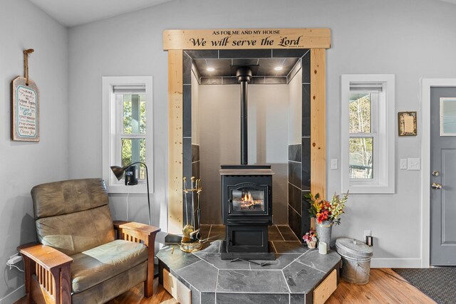 living area with a wood stove, wood finished floors, and baseboards
