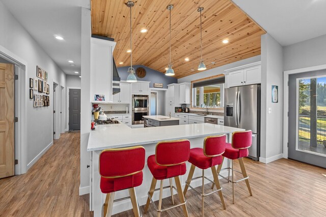 kitchen featuring decorative backsplash, a sink, appliances with stainless steel finishes, vaulted ceiling, and a peninsula