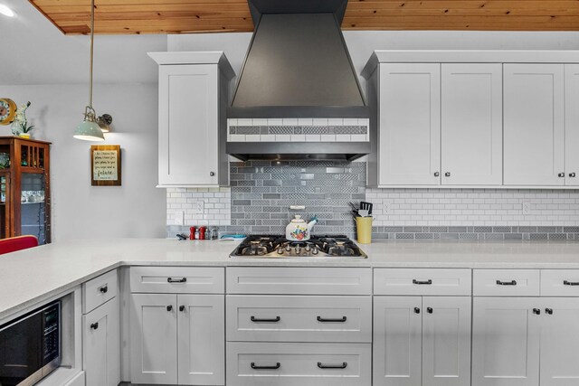 kitchen with wall chimney range hood, stainless steel gas stovetop, and light countertops