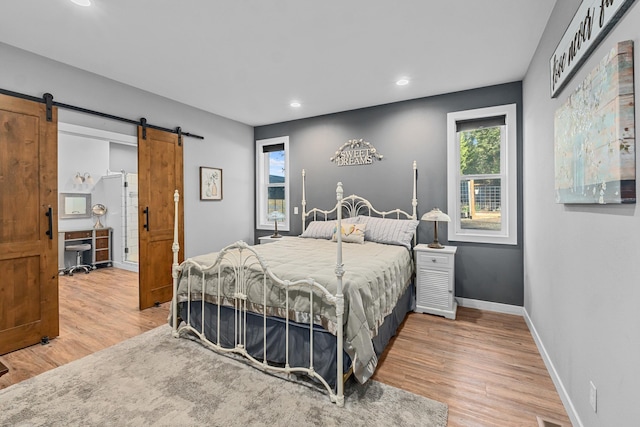 bedroom featuring recessed lighting, wood finished floors, a barn door, and baseboards