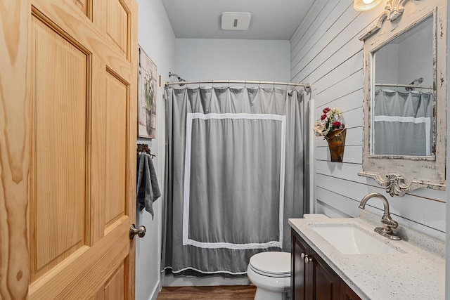 full bath with wood walls, wood finished floors, toilet, and vanity