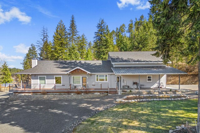 farmhouse-style home featuring a chimney, a front yard, and a deck