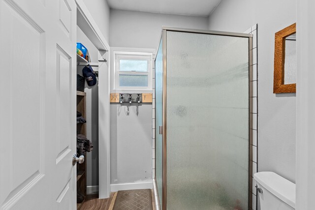 bathroom with toilet, a shower stall, and baseboards