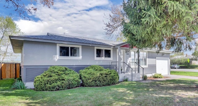 view of front of property featuring a front lawn, stucco siding, an attached garage, and fence