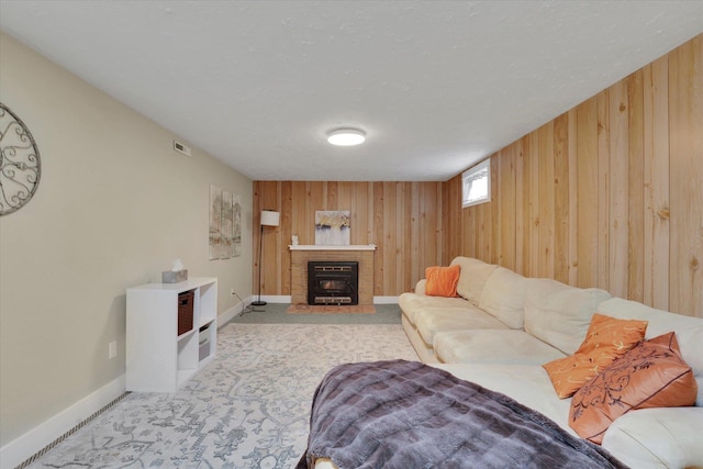 living room with a fireplace with flush hearth, wooden walls, baseboards, and carpet floors