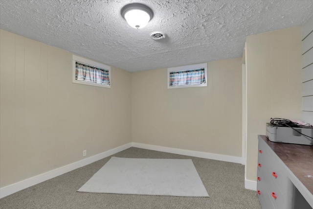 basement with a textured ceiling, carpet flooring, and baseboards