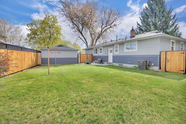 rear view of property with a chimney, fence, central AC unit, and a lawn