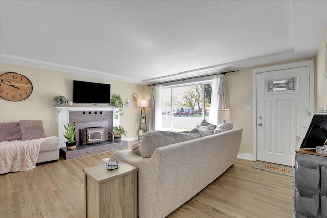 living room featuring a wood stove, light wood finished floors, and baseboards