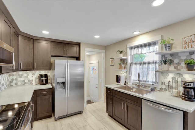 kitchen with tasteful backsplash, open shelves, a sink, stainless steel appliances, and dark brown cabinetry