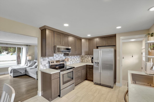 kitchen featuring recessed lighting, appliances with stainless steel finishes, light countertops, dark brown cabinets, and backsplash