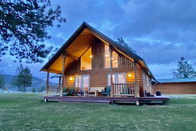 rear view of property with french doors, a wooden deck, and a yard