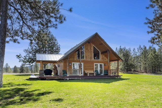 back of property featuring metal roof, a lawn, and a wooden deck