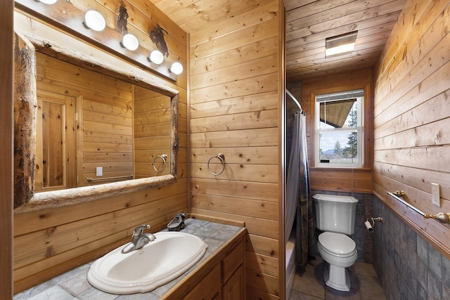 full bathroom featuring wood ceiling, wooden walls, toilet, tile patterned floors, and vanity