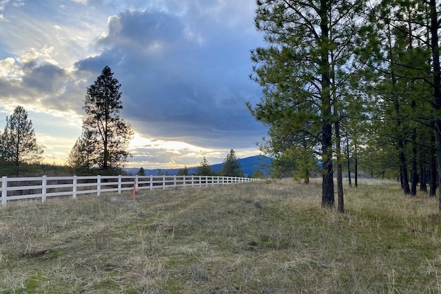 yard at dusk featuring fence and a rural view