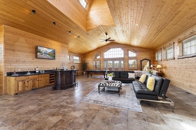 living area with wood ceiling, stone finish flooring, wooden walls, and ceiling fan