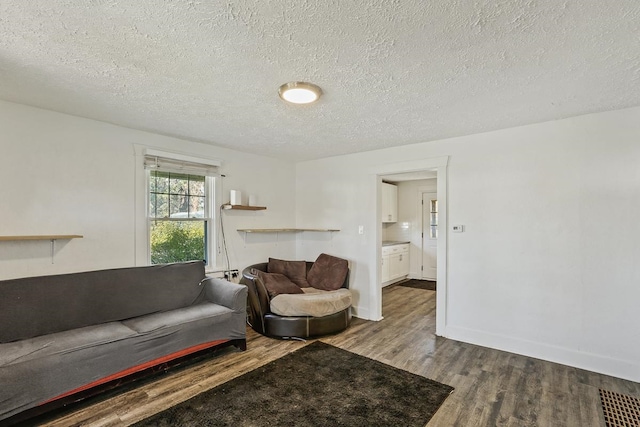 living room featuring a textured ceiling, wood finished floors, and baseboards